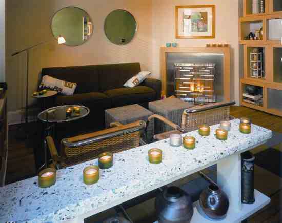 The living room features a fireplace with a metal grille by Charles Danley, a low room divider topped with colorful recycled glass terazzo and carpet squares made from recycled plastic bottles.